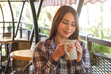 Genç ve güzel bir kadının portresi. Lokantada bir fincan kakao w / marshmallow içerken. Soğuk sonbahar gününde sıcak bir içecek içmekten tatmin olan neşeli bir kadın. Kopyalama alanını kapat