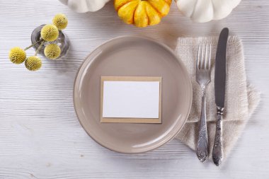 Şükran Günü masa hazırlama konsepti. Geleneksel bayram sembolü olarak seramik tabak, çatal, bıçak ve mini balkabağı. Üst görünüm, kapat, boşluğu kopyala, arkaplan.