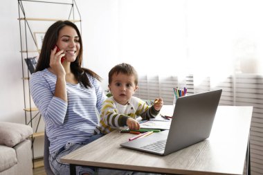 İki yaşındaki oğluna resim çizmeyi öğreten çok yönlü çalışan genç ve güzel bir kadın. Küçük kızıyla kaliteli zaman geçiren bir kadın. Evde eğitim kavramı. Kapat, kopyala boşluk, arkaplan.