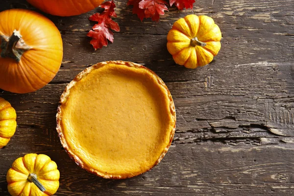 Traditional thanksgiving food on wooden table. Orange delicious homemade pumpkin pie with crust and decorative items. Thanksgiving table setting concept.Top view, close up, copy space, background.