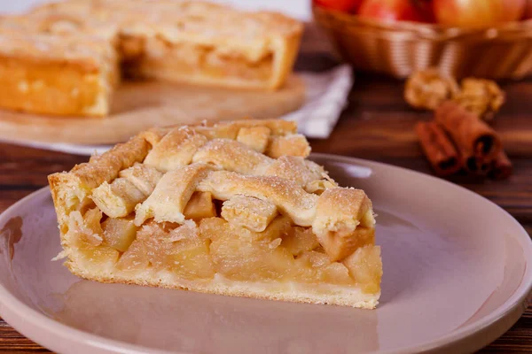 Traditional American Thanks Giving pie with whole organic apples, cinnamon sticks on wooden table. Homemade fruit tart baked to golden crust. Close up, copy space, top view, background.