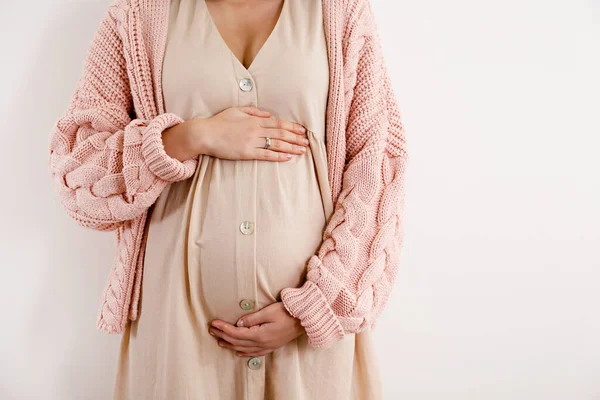 年轻漂亮的女人在怀孕的第二个季度 身穿粉色超大针织毛衣 腹部有胳膊的怀孕女性的剪影 期待一个孩子的概念 孤立的背景 复制空间 — 图库照片
