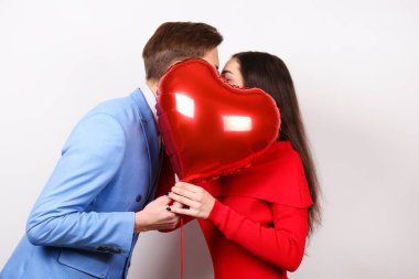 Sevgililer Günü konseptin kutlu olsun. Birbirlerine aşık çiftlerin kalp şeklinde bir balonu tutarken çekilmiş bir fotoğraf. 14 Şubat, sevgililer günü. Beyaz arkaplan, kopyalama alanı, ön görünüm portresi.