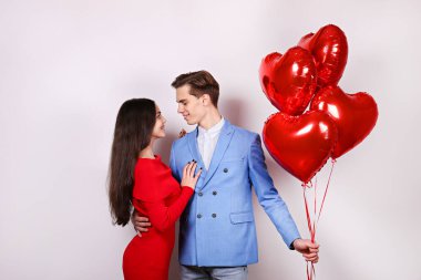 Sevgililer Günü konseptin kutlu olsun. Birbirlerine aşık çiftlerin kalp şeklinde bir balonu tutarken çekilmiş bir fotoğraf. 14 Şubat, sevgililer günü. Beyaz arkaplan, kopyalama alanı, ön görünüm portresi.