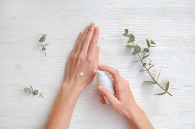 Aşırı sabun ve dezenfektan kullandıktan sonra iyileşme ve iyileşme için el kreminin canlandırılması. Genç bir kadın nemlendirici losyon sürüyor. Boşluğu kopyala, kapat, pembe arkaplan, düz alan, üst görünüm.