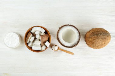 Hindistan cevizi bir gıda kaynağı ve kozmetik üründür. Tahta bir kasede kırık meyve ve ahşap desenli masada bir kavanoz nemlendirici krema. Kapat, üst görünüm, kopyala boşluk, düz alan, arkaplan.