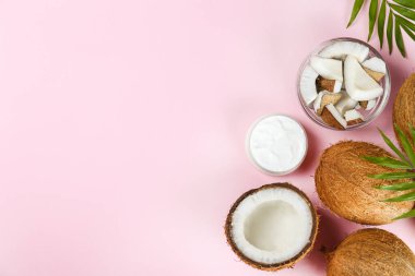 Hindistan cevizi bir gıda kaynağı ve kozmetik üründür. Tam ve çatlak meyve, bir kavanoz nemlendirici krema ve yağ, pembe masa üstünde kaşık ve palmiye yaprağı. Kapat, üst görünüm, kopyala boşluk, düz alan, arkaplan.