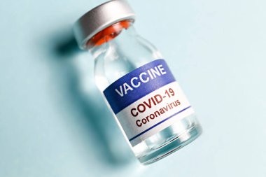 Kovid 19 virüsüne karşı aşı için makro doz antiviral aşı şişesi. Metin için kopyalama alanı olan mavi arkaplanda izole edilmiş. Kapat, üst görünüm.