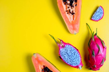 Papaya ve pitaya - yüksek miktarda lif ve magnezyum içeren egzotik düşük kalorili besin yoğunluğunda meyveler. Tam ve yarı yarıya, görülebilir posalı doku, izole edilmiş sarı arkaplan. Kapat, boşluğu kopyala, üst görünüm