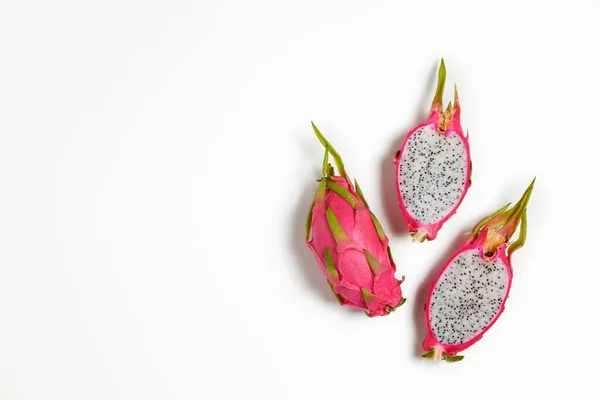Pitaya - an exotic low-calorie nutrient-dense fruit with high amount of fiber and magnesium. Whole and halved dragon fruit with visible pulp texture, isolated on white. Close up, copy space, top view.
