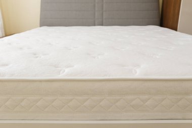 Yatağın üstündeki beyaz ortopedik şiltenin yakın çekim görüntüsü. Omurga büyümesi ve basınç noktası rahatlaması için hipoalerjenik köpük matress. Arkaplan, boşluğu kopyala.