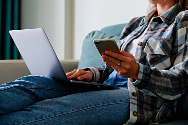 Work from home concept. Cropped shot of a distracted woman scrolling social media on her phone. Female freelancer working at her living room. Close up, copy space for text.