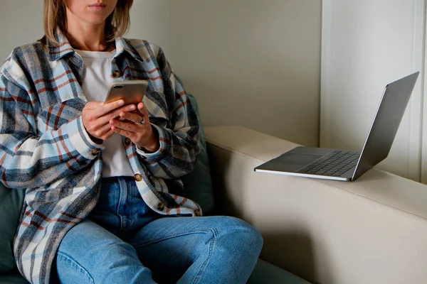 Work from home concept. Cropped shot of a distracted QA engineer woman testing and comparing desktop and mobile software. Female freelancer working at her living room. Close up, copy space for text.