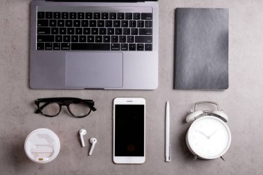 Minimalist çalışma alanının kırpılmış görüntüsü. Metalik gri dizüstü bilgisayarlı beton desenli bir masa. Müteahhit konseptinin işyeri. Arkaplan, metin için boşluk kopyala, düz yat, kapat, üst görünüm.