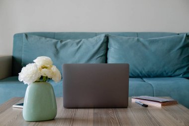 Merkez ofis konsepti. Oturma odasındaki çalışma alanından. Modern laptop, cep telefonu, defter ve vazo, üzerinde çiçekler olan ahşap masa. Kapat, kopyala boşluk, arkaplan.