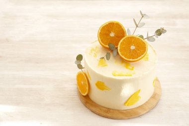 Beyaz kremalı, dilimlenmiş turuncu ve okaliptüs süslemeli minimalist tek katlı düğün pastası. Kapat, metin, arkaplan ve üst görünüm için boşluk kopyala.