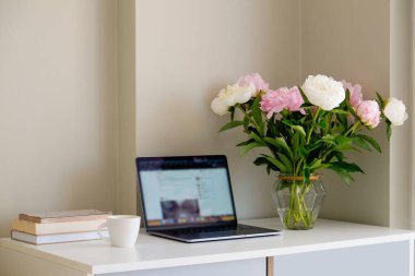 Merkez ofis konsepti. Pencerenin yakınındaki ev bölgesinden atanmış bir iş. Modern dizüstü bilgisayar, defter ve vazo. Masada çiçekler var. Kapat, kopyala boşluk, arkaplan.