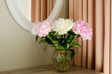 Gri duvar arkaplanının üzerinde cam bir vazoda duran güzel şakayık çiçeklerinin bir stüdyo fotoğrafı ve metin için bir sürü fotokopi alanı. Kadınsı çiçek kompozisyonu. Kapat, arkaplan.