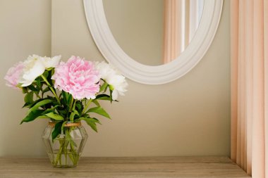 Gri duvar arkaplanının üzerinde cam bir vazoda duran güzel şakayık çiçeklerinin bir stüdyo fotoğrafı ve metin için bir sürü fotokopi alanı. Kadınsı çiçek kompozisyonu. Kapat, arkaplan.