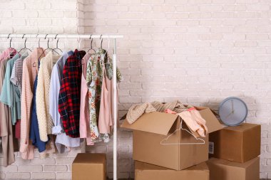 Boş, imzasız, taşınmamış kutular ve yeni boş bir dairede askıda asılı giysiler. Geniş mobilyalı, paketsiz karton kutu yığını olan bir oda. İç arkaplan, metin için kopyalama alanı.