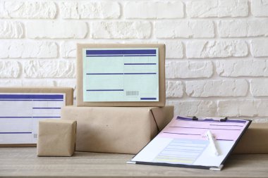 Kargo etiketli el sanatları kağıdına sarılı farklı boyutlarda paketler. Masada bir sürü paket kutusu var. Kapat, metin için boşluk kopyala, beyaz tuğla duvar arkaplanı.
