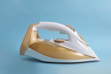 Stüdyo yakın çekim beyaz ve altın kablosuz buhar ütüsü mavi arkaplan izole metin için bir sürü kopya alanı ile.