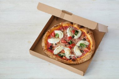 Bufalo mozzarella ile fırında pizza, parmesanlı reggiano peyniri, fesleğen ve ançüezli sandviç. Beyaz ahşap masa arkaplanlı geleneksel İtalyan yemeği. Kapat, boşluğu kopyala, üst görünüm.