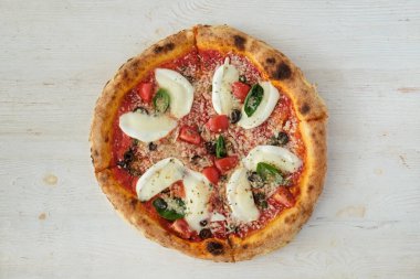 Bufalo mozzarella ile fırında pizza, parmesanlı reggiano peyniri, fesleğen ve ançüez. Beyaz ahşap masa arkaplanlı geleneksel İtalyan yemeği. Kapat, boşluğu kopyala, üst görünüm.