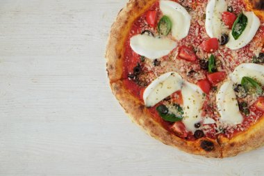 Bufalo mozzarella, parmesanlı reggiano peynirli, fesleğenli ve ançüezli fırında pizza. Geleneksel İtalyan yemeği ahşap desenli masa arkaplanı. Kapat, boşluğu kopyala, üst görünüm.