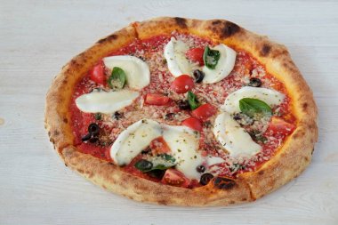 Bufalo mozzarella ile fırında pizza, parmesanlı reggiano peyniri, fesleğen ve ançüez. Beyaz ahşap masa arkaplanlı geleneksel İtalyan yemeği. Kapat, boşluğu kopyala, üst görünüm.