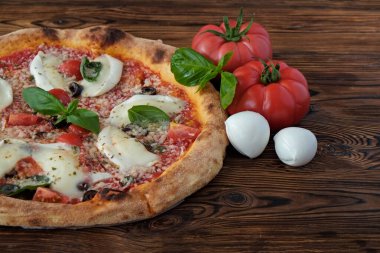 Bufalo mozzarella, parmesanlı reggiano peynirli, fesleğenli ve ançüezli fırında pizza. Geleneksel İtalyan yemeği ahşap desenli masa arkaplanı. Kapat, boşluğu kopyala, üst görünüm.