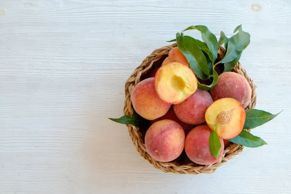 Stelletje Rijpe Biologische Perziken Een Rieten Schaal Witte Houten Tafelondergrond — Stockfoto