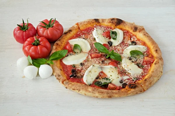 Bufalo mozzarella ile fırında pizza, parmesanlı reggiano peyniri, fesleğen ve ançüez. Beyaz ahşap masa arkaplanlı geleneksel İtalyan yemeği. Kapat, boşluğu kopyala, üst görünüm.