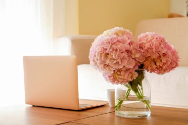 Merkez ofis konsepti. Memleketten atanmış bir iş. Modern dizüstü bilgisayarı ve masasında çiçekler olan vazosu olan kadınsı çalışma alanı. Kapat, kopyala boşluk, arkaplan.