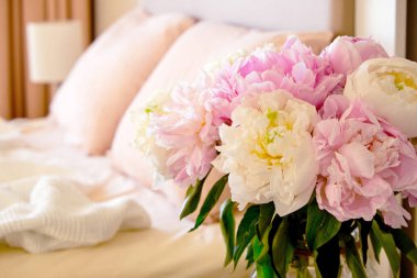 Komodinin yakın çekimini yapılmamış yatağın yanındaki cam vazoda bir buket şakayıkla yap. Günaydın konsepti. Yatak odası doğal ışıkla dolu. Metin, arkaplan ve üst görünüm için boşluk kopyala.