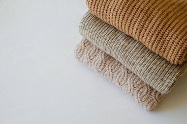 Bir sürü örülmüş pastel renkli süveter farklı örgü desenleri yığılmış, açıkça görülebilen doku. Şık sonbahar kış mevsimi örgü giysileri. Kapat, metin için boşluk kopyala.