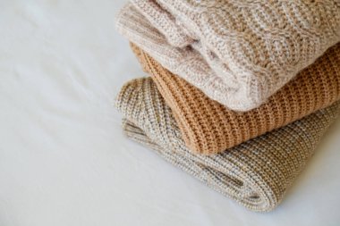 Bir sürü örülmüş pastel renkli süveter farklı örgü desenleri yığılmış, açıkça görülebilen doku. Şık sonbahar kış mevsimi örgü giysileri. Kapat, metin için boşluk kopyala.