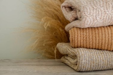 Bir sürü örülmüş pastel renkli süveter farklı örgü desenleri yığılmış, açıkça görülebilen doku. Şık sonbahar kış mevsimi örgü giysileri. Kapat, metin için boşluk kopyala.