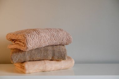 Bir sürü örülmüş pastel renkli süveter farklı örgü desenleri yığılmış, açıkça görülebilen doku. Şık sonbahar kış mevsimi örgü giysileri. Kapat, metin için boşluk kopyala.