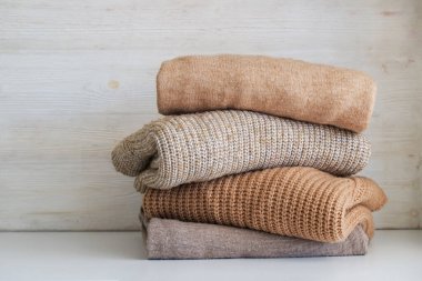 Yatak odasındaki şifoniyerin üstünde temiz, yeni yıkanmış, düzgün katlanmış giysiler yığını. Pastel renkli süveter yığını. Boşluğu kopyala, kapat, arkaplan.