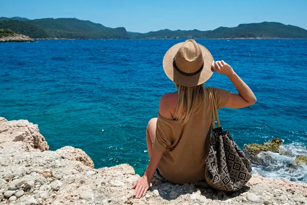 広いつばの藁帽子とデニムのショートパンツを被った若い女性が海の景色を楽しんでいます 地中海の島々を見るヒップスター女性 スペースをコピーし — ストック写真