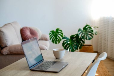 Merkez ofis konsepti. Pencerenin yakınındaki ev bölgesinden atanmış bir iş. Modern dizüstü bilgisayar, defter ve vazo. Masada çiçekler var. Kapat, kopyala boşluk, arkaplan.