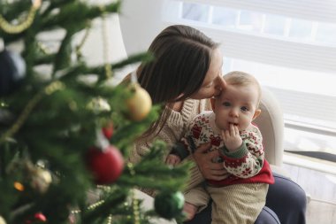 Anne bebeğiyle Noel ağacının yanında.