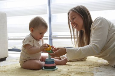 Anne ve bebek piramit oyuncaklarını üst üste istifleyerek oynuyorlar. Boşluğu kopyala, arkaplan.