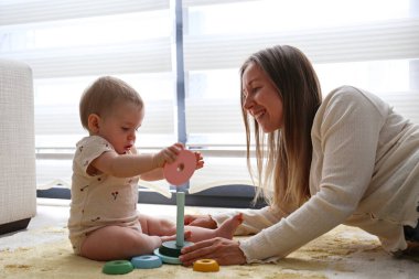 Anne ve bebek piramit oyuncaklarını üst üste istifleyerek oynuyorlar. Boşluğu kopyala, arkaplan.