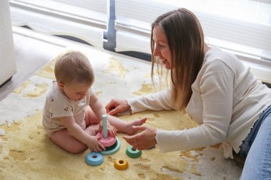 Anne ve bebek piramit oyuncaklarını üst üste istifleyerek oynuyorlar. Boşluğu kopyala, arkaplan.