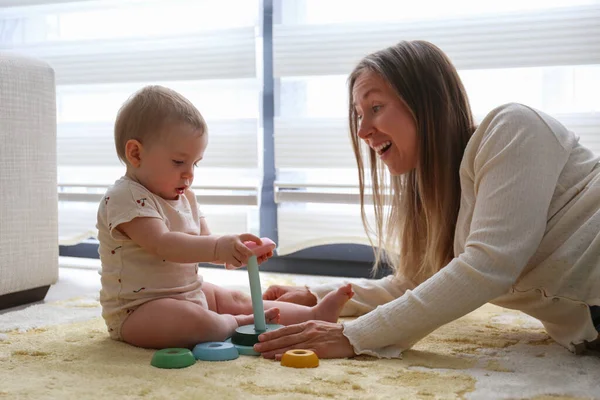 Anne ve bebek piramit oyuncaklarını üst üste istifleyerek oynuyorlar. Boşluğu kopyala, arkaplan.