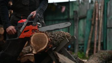 Bir adam testereyle odun kesiyor..