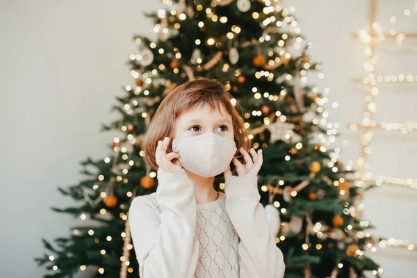 girl meets Christmas in the covid-19 pandemic. Child in a protective medical mask. Quarantine isolation social distance. New year holidays 2021. Kid in Face cover