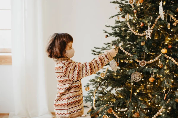 Criança Vestindo Camisola Quente Proteção Máscara Decorar Árvore Natal Casa — Fotografia de Stock